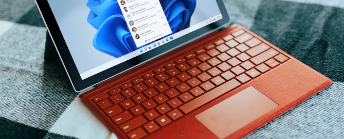 Red Surface laptop on a checkered bed by a window